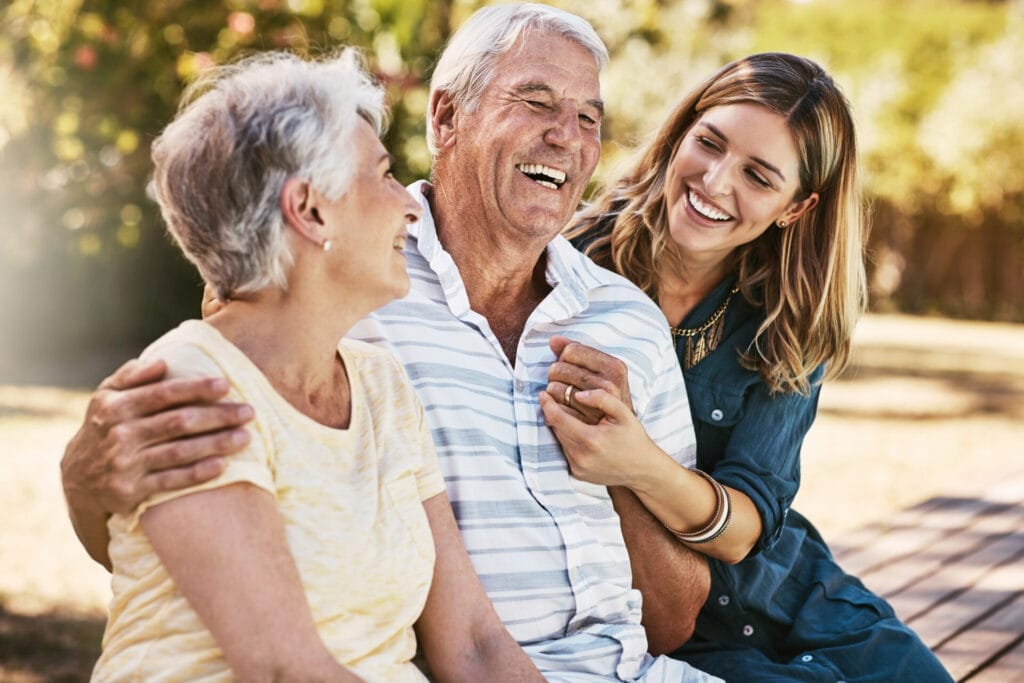 woman, grandparents and hug for family summer vacation, holiday or break together in the outdoors. happy grandma, grandpa and daughter with smile in joyful happiness, love or care for elderly parents